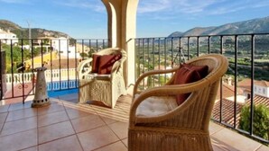 A balcony with wicker chairs and a tiled floor, overlooking a scenic landscape with hills and buildings. - Lovely Villa with gorgeous views - Sleeps 6 (Heated Pool) (L'Atzúbia)