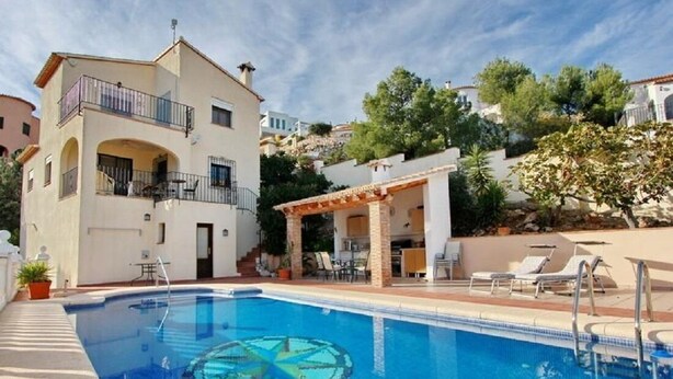 A swimming pool with a circular water feature, a covered outdoor seating area, and a building with a balcony. - Lovely Villa with gorgeous views - Sleeps 6 (Heated Pool) (L'Atzúbia)
