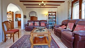 A spacious living room with a large leather sofa, a wooden coffee table, and a bookshelf. - Lovely Villa with gorgeous views - Sleeps 6 (Heated Pool) (L'Atzúbia)