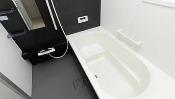 Un bagno moderno con una vasca da bagno bianca, un mobile lavabo nero con specchio e un portasciugamani bianco.