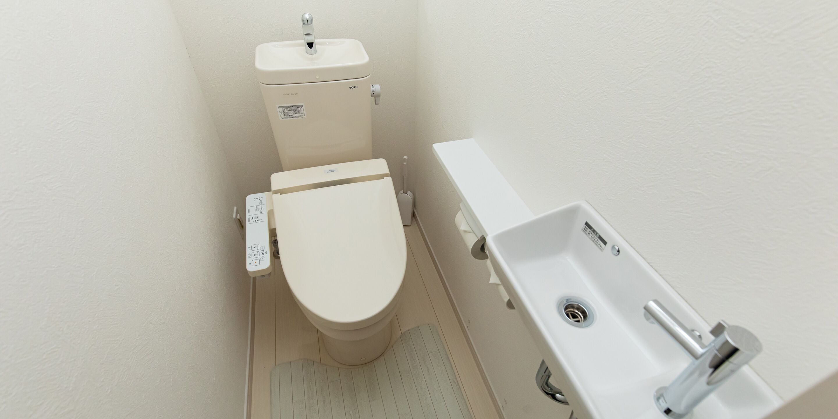A small, white bathroom with a toilet, a sink, and a shower.