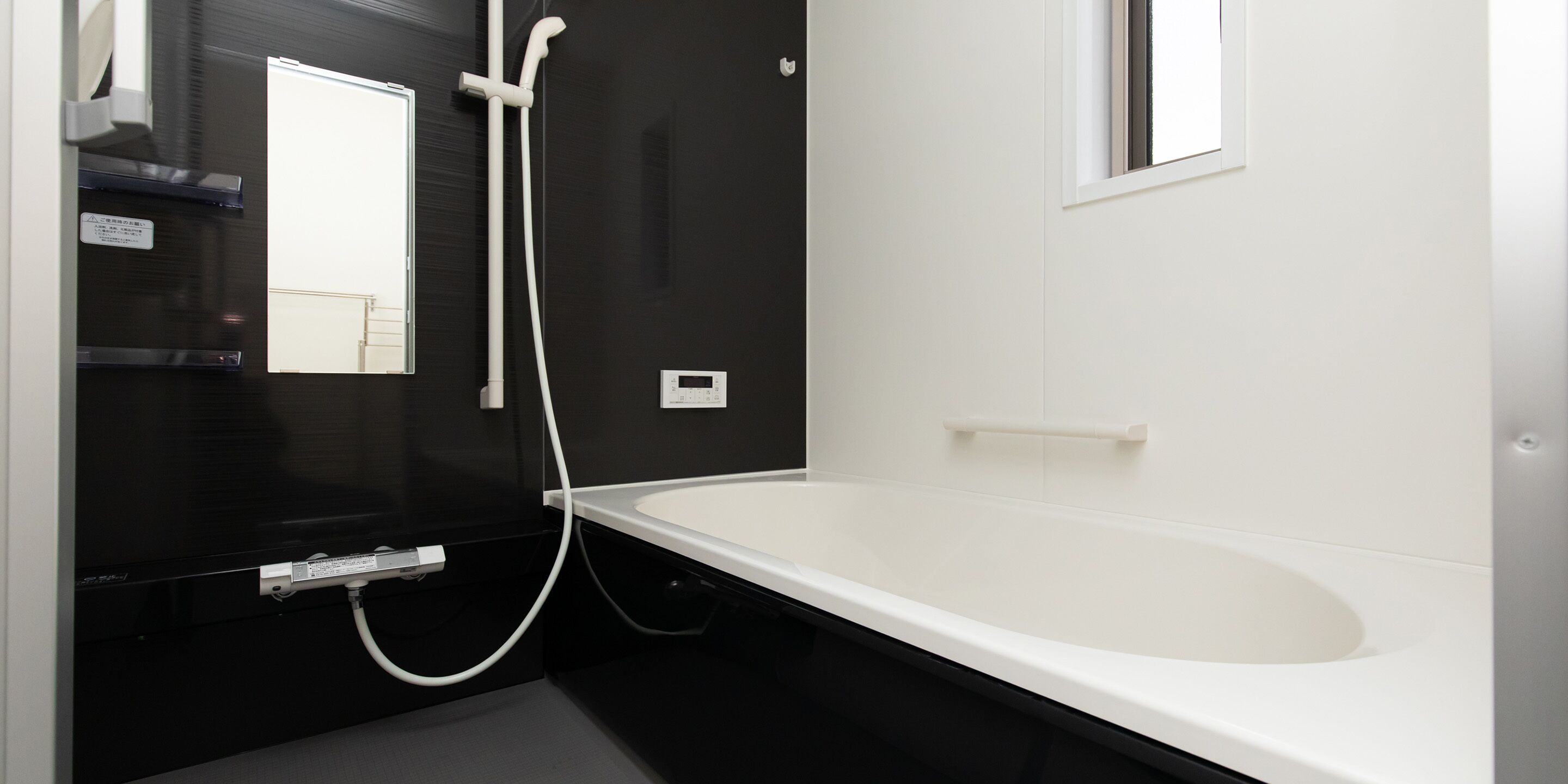 A modern bathroom with a white bathtub, a black vanity, and a shower area.