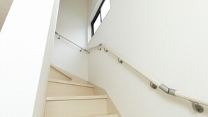 A staircase with a handrail and a window above.