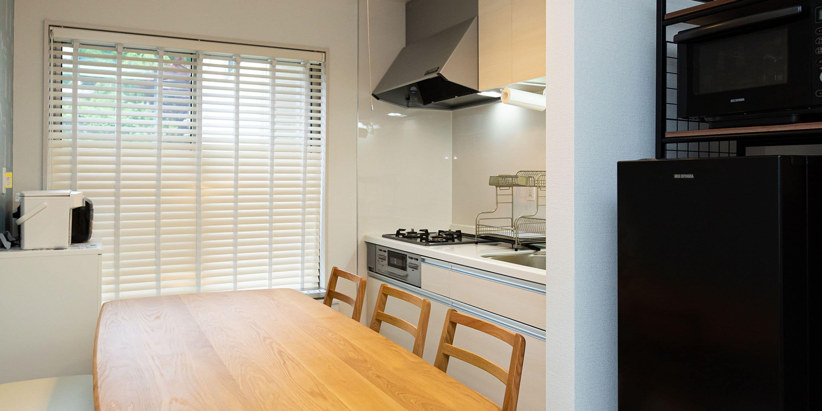 A compact kitchen with a dining table, chairs, a stove, and a microwave.