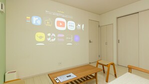 A room with a projection of various app icons on the wall, a wooden table with a chair, and a wardrobe.