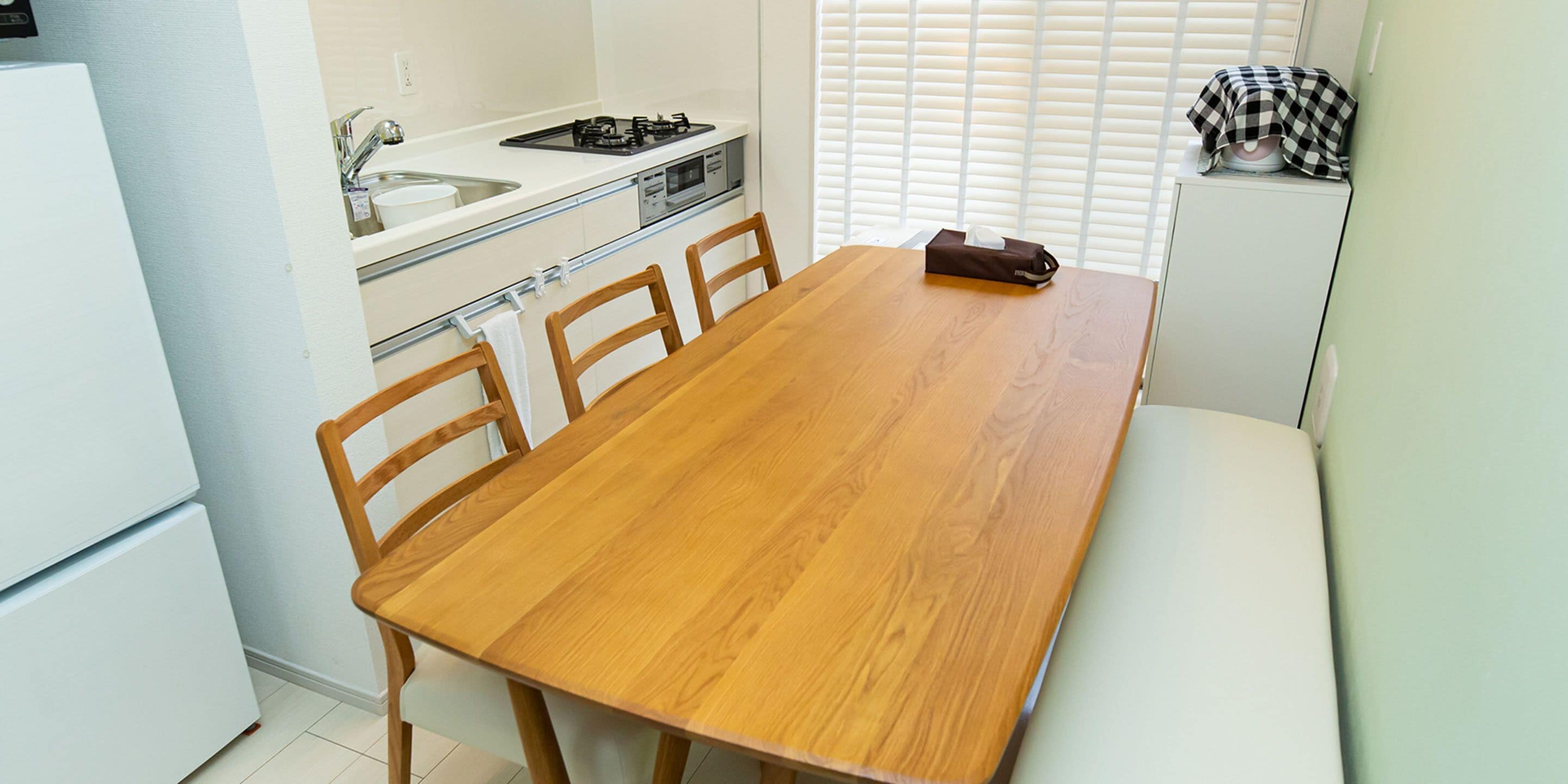A compact kitchen with a wooden dining table, chairs, a sink, and a stove.