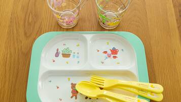 Une table avec un plateau vert, deux verres transparents ornés de motifs floraux et un ensemble de couverts.