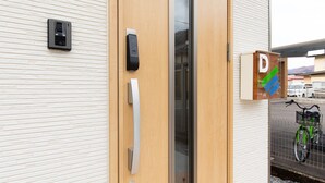 A building entrance with a wooden door, a security camera, and a sign indicating a parking area.