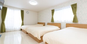 A hotel room with two single beds, a wooden headboard, a white clock on the wall, and green curtains on the windows. - Kinugawa Station Front (Nikko)