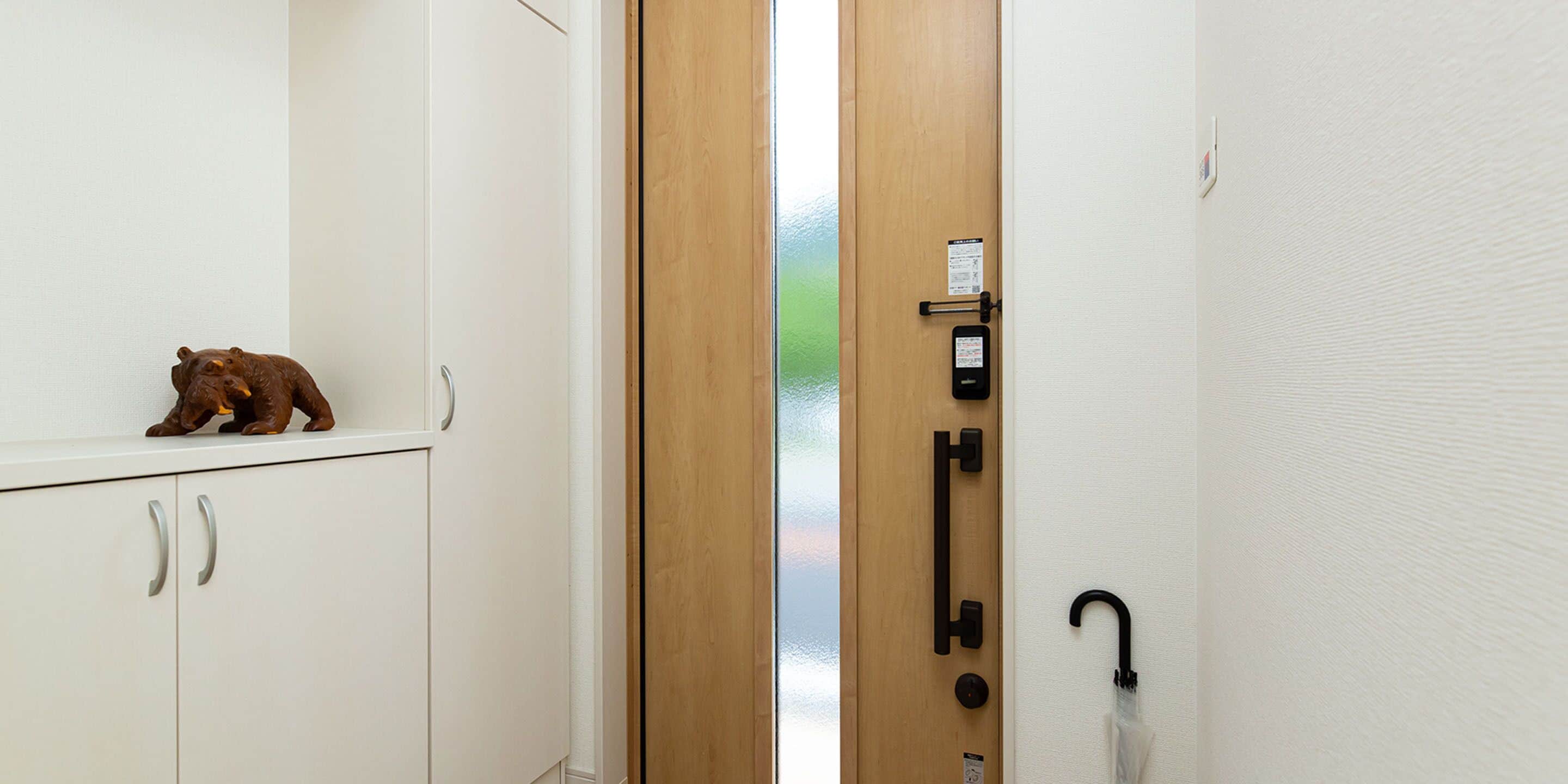 A room with a wooden door, a white wall, and a bear figurine on a cabinet.