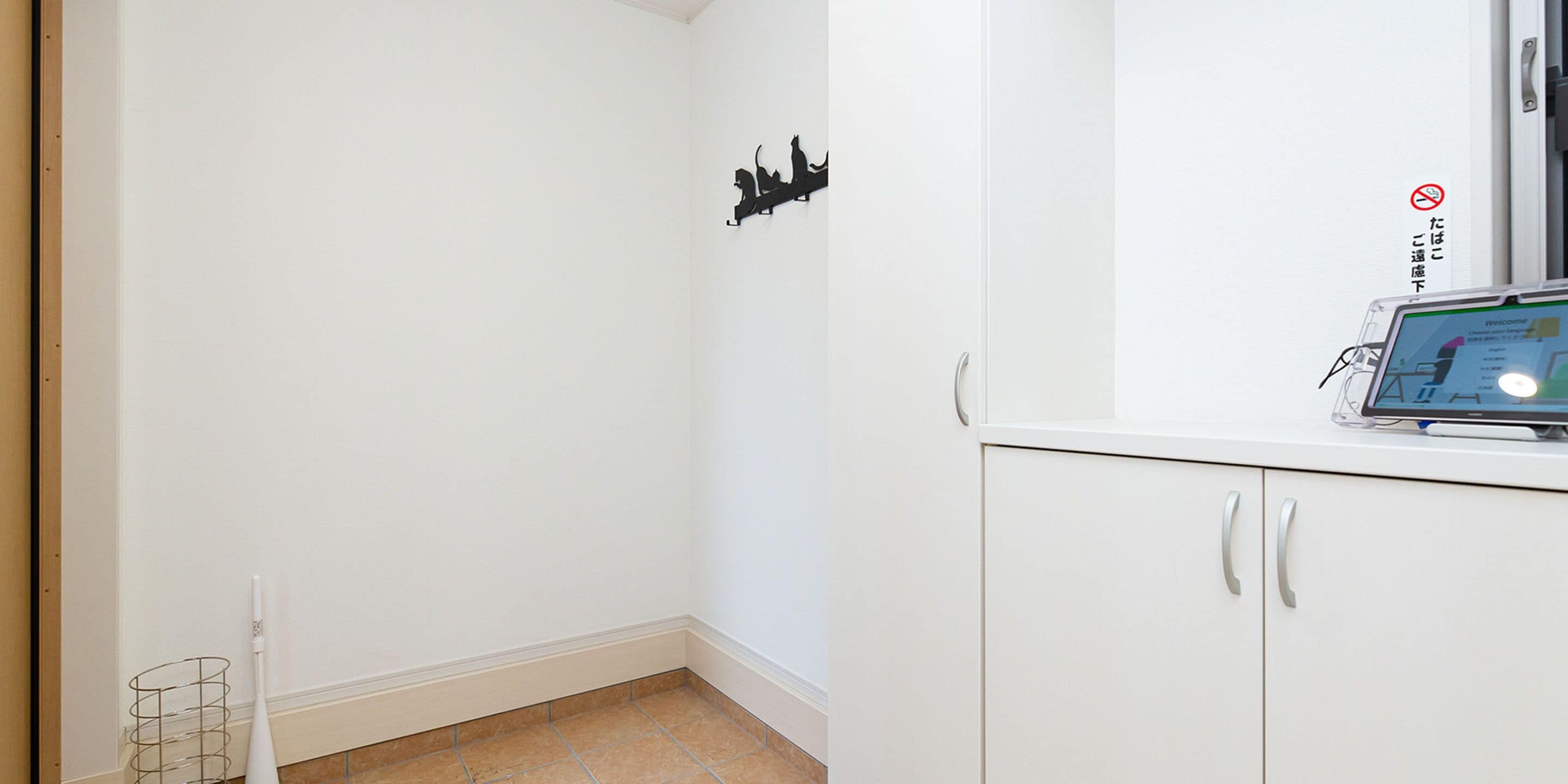 Un rincón de una habitación con un armario blanco, un adorno en silueta negra en la pared y un cartel de prohibido fumar.
