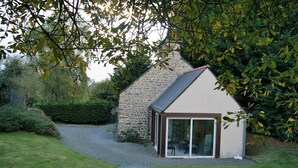 A stone house with a sloped roof and a glass door leading to an outdoor seating area. - Charming house set in grounds and forest, guaranteed peace and quiet. (Gommenec'h)
