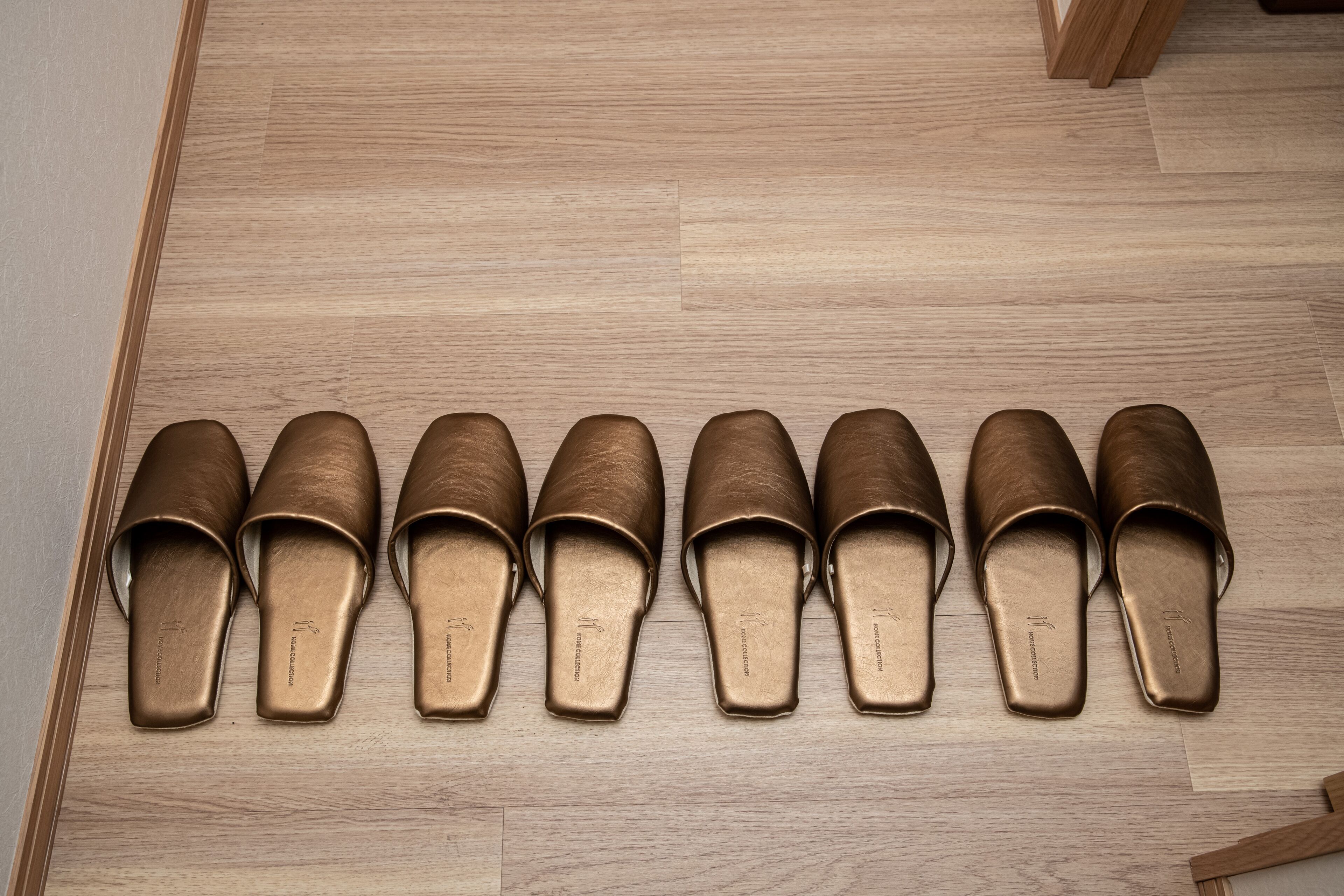A row of eight brown shoes on a wooden floor.