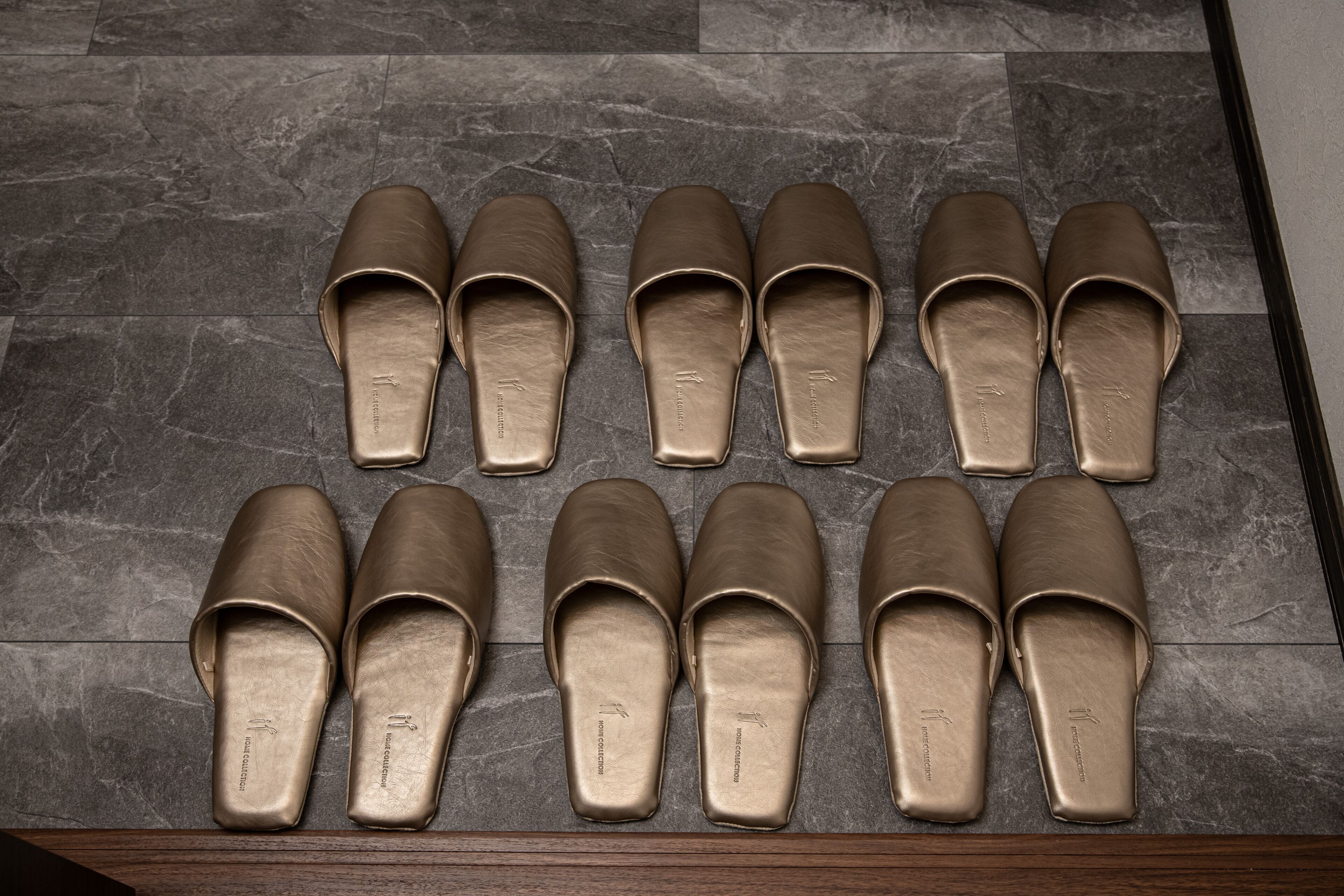 Un par de zapatos marrones de vestir sobre un piso de baldosas oscuras.