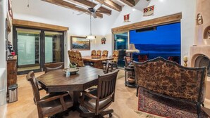A dining area with a wooden table and chairs, a ceiling fan, and a view of the outdoors. - Secluded Desert Oasis: Luxurious Inn-Abiquiu Lake Views-Daily Gourmet Breakfast. (Abiquiu)