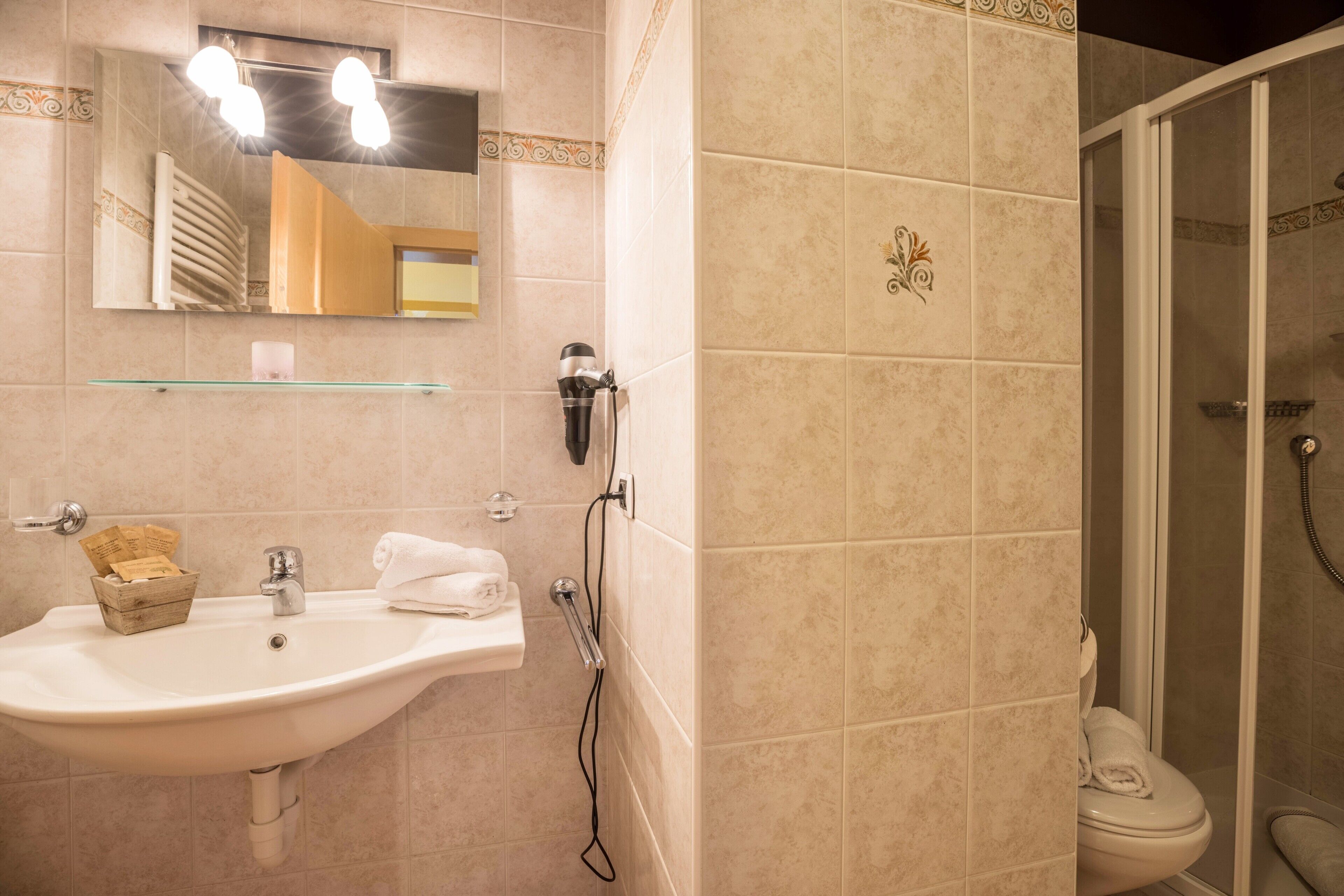 Une salle de bain équipée d’un lavabo, d’un miroir, d’un porte-serviettes et d’une zone douche.
