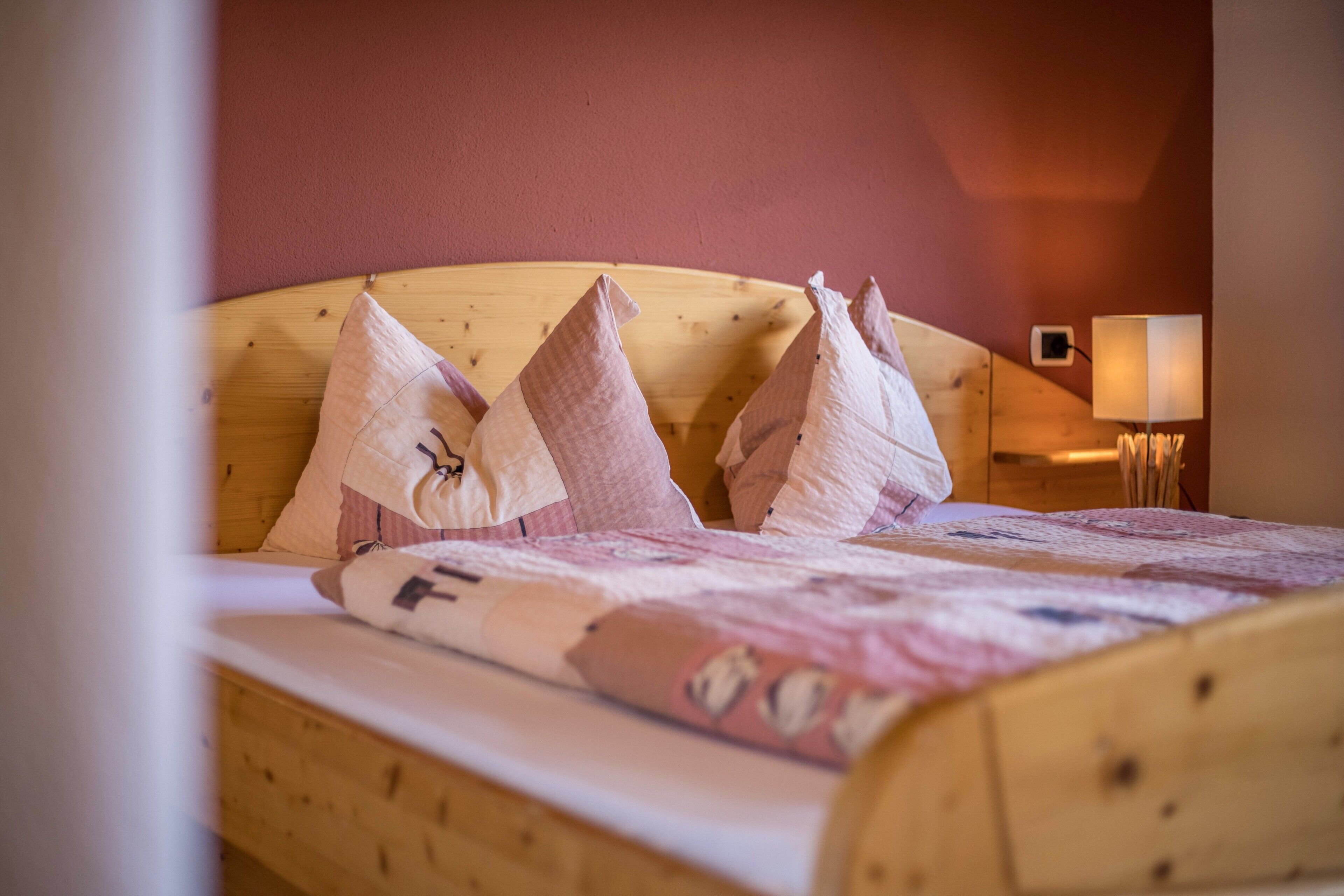 Una cama con cabecera de madera, almohadas y colcha.