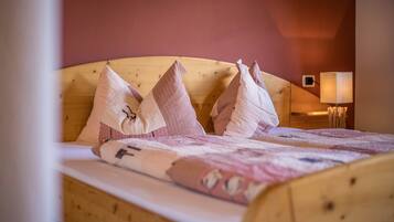 Una cama con cabecera de madera, almohadas y colcha.