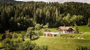 Une maison avec un grand jardin et une vue sur une colline boisée.