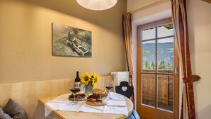 Une table à manger recouverte d’une nappe blanche, avec des verres à vin, une bouteille de vin, un panier de pain et une assiette de nourriture.