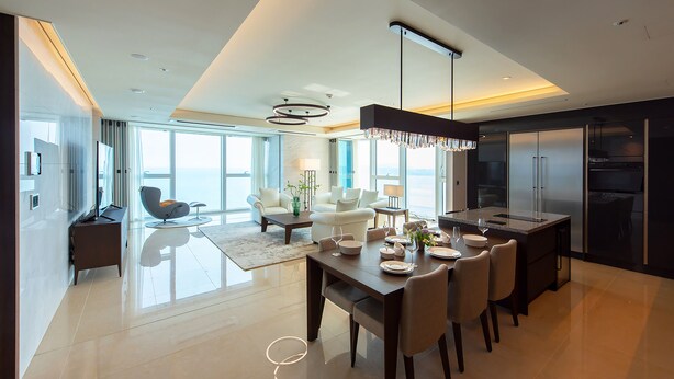Una cocina moderna con comedor, ventanas amplias y vista al mar.