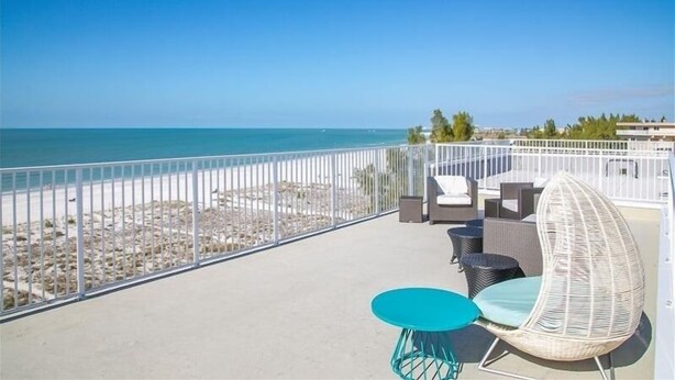 A balcony with a view of the beach, outdoor furniture, and a railing. - Oceana 201W See gorgeous sunsets! (Treasure Island)