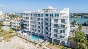 A multi-story hotel with balconies, a swimming pool, and a view of the beach and water. - Oceana 201W See gorgeous sunsets! (Treasure Island)