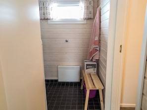 A small, narrow bathroom with a window, a towel rack, a heater, and a box of KATRIN cover sheets.