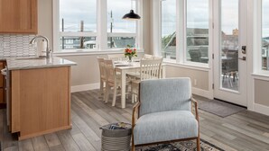 A modern kitchen with a wooden island, a dining area with a table and chairs, and large windows offering views of the cityscape. - AC, kayaks, rooftop deck with fire pit, boat launch and incredible views! (Camano)