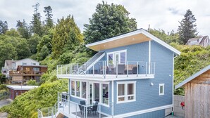 A two-story house with a balcony, a staircase, and a garage. - AC, kayaks, rooftop deck with fire pit, boat launch and incredible views! (Camano)