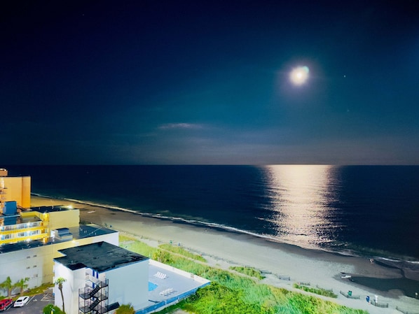 A coastal hotel with a beach view, a pool, and a parking area.