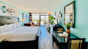 Een hotelkamer met een bed, bureau, stoel, een kamerplant en uitzicht op de stad.