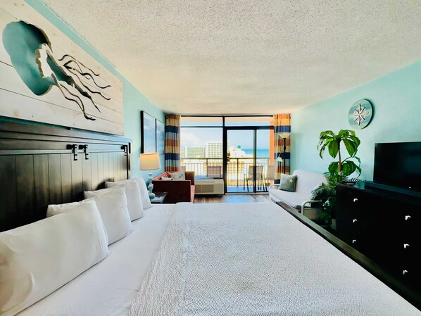 Une chambre d’hôtel avec un grand lit, une télévision, un bureau et un balcon avec vue.