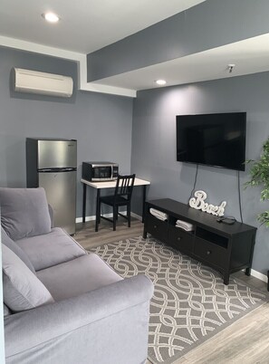 Relax in this stylish living room with a sofa, dining table, and flat-screen TV.