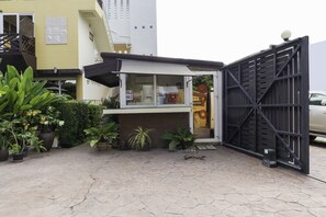 A small outdoor cafe with a black gate, potted plants, and a tiled patio. - OYO 1005 Pacotte Boutique Resort (Rawai)
