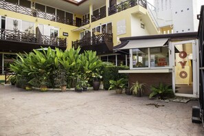 A courtyard with potted plants, a building entrance, and a sign that reads "OYO". - OYO 1005 Pacotte Boutique Resort (Rawai)
