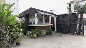 A building with a gated entrance, potted plants, and a sign with the word "PACOTTE". - OYO 1005 Pacotte Boutique Resort (Rawai)