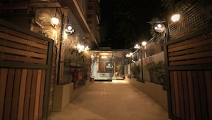 Un chemin bordé de barrières menant à un bâtiment la nuit, éclairé par de nombreux luminaires.