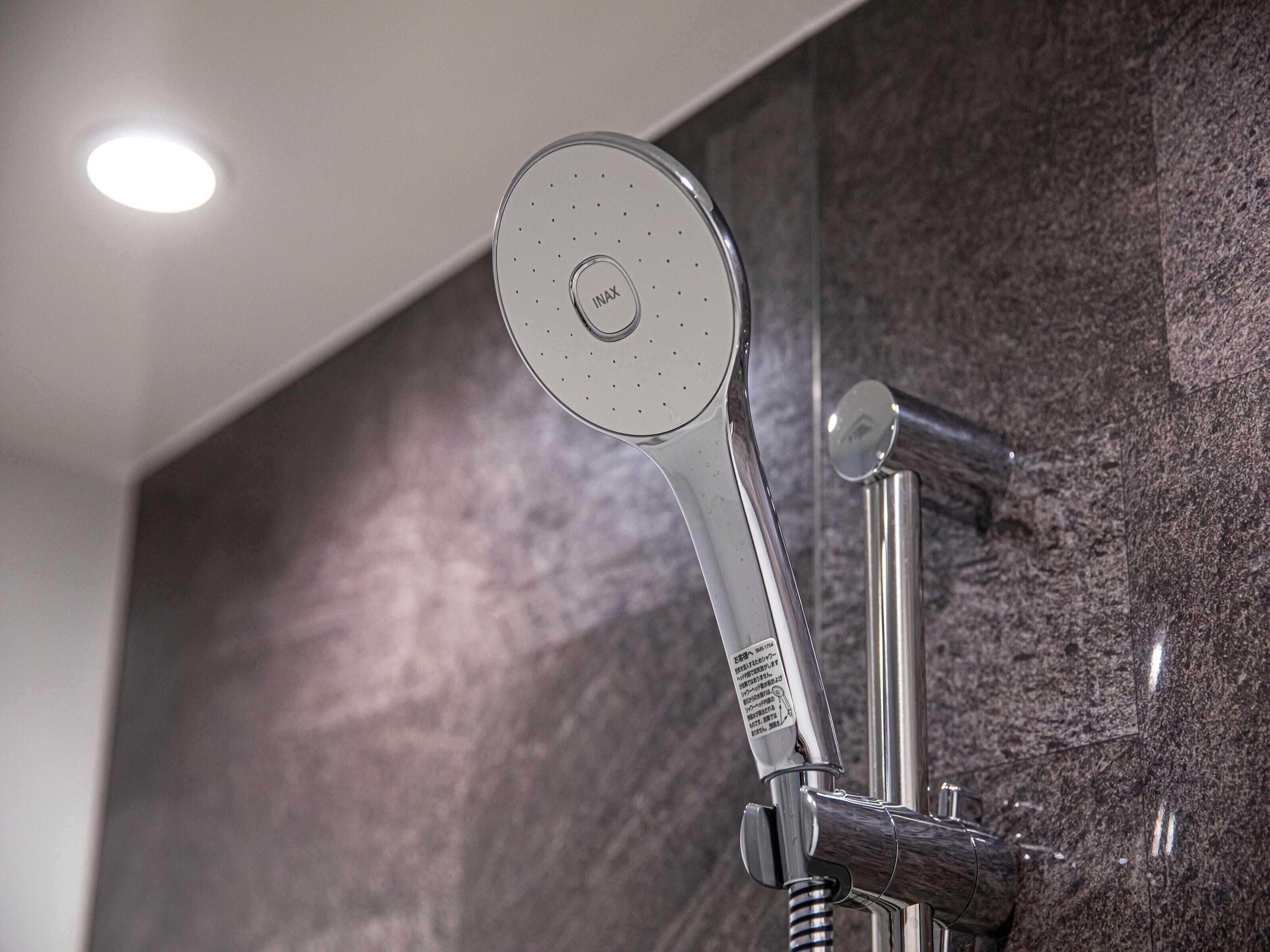 Un cabezal de ducha moderno con un panel de control, fijado a una pared con superficie texturizada.