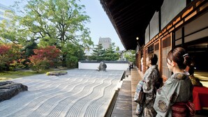Un jardin japonais traditionnel, avec une lanterne en pierre, des bancs en bois et des visiteurs vêtus de costumes traditionnels.