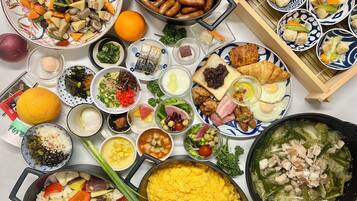 A table with various dishes including sausages, vegetables, and a pot of soup.