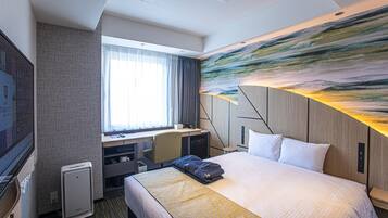 A hotel room with a large bed, a desk, a chair, and a TV.