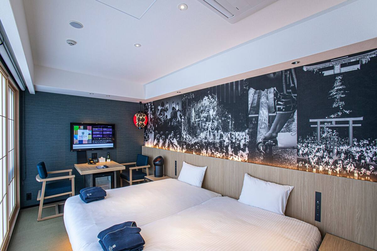 Une chambre d’hôtel avec un grand lit, un bureau avec un ordinateur et un téléviseur fixé au mur.