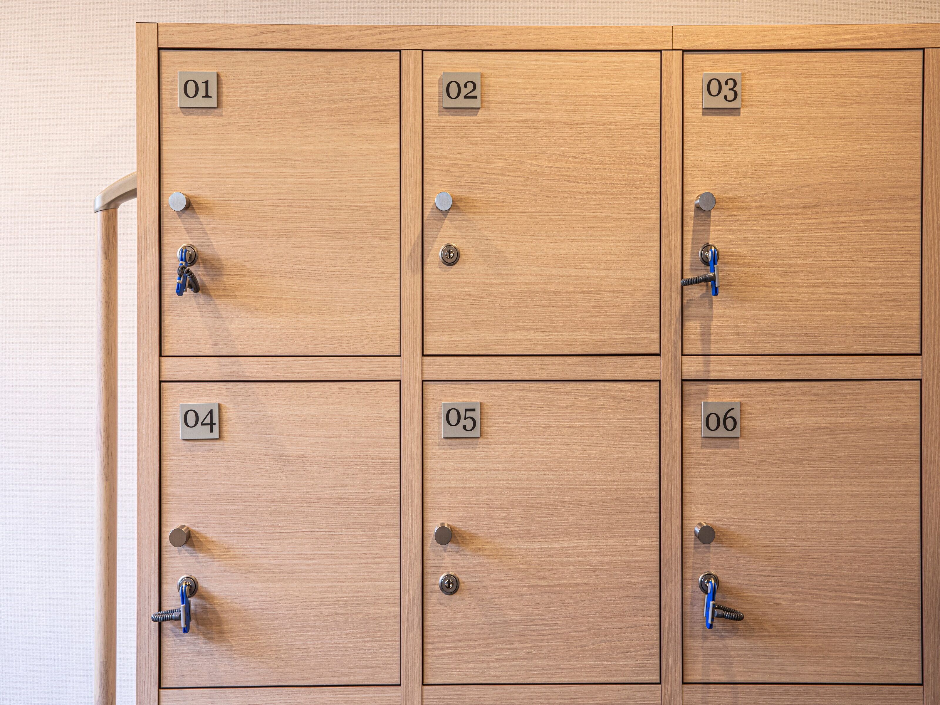 A set of six wooden lockers with numbered locks, each featuring a keyhole and a key.