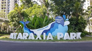 Ein Schild für Taraxia Park mit blau-weißem Design, das eine stilisierte Pflanze zeigt und den Text „Forest City Countryside Garden“ trägt.