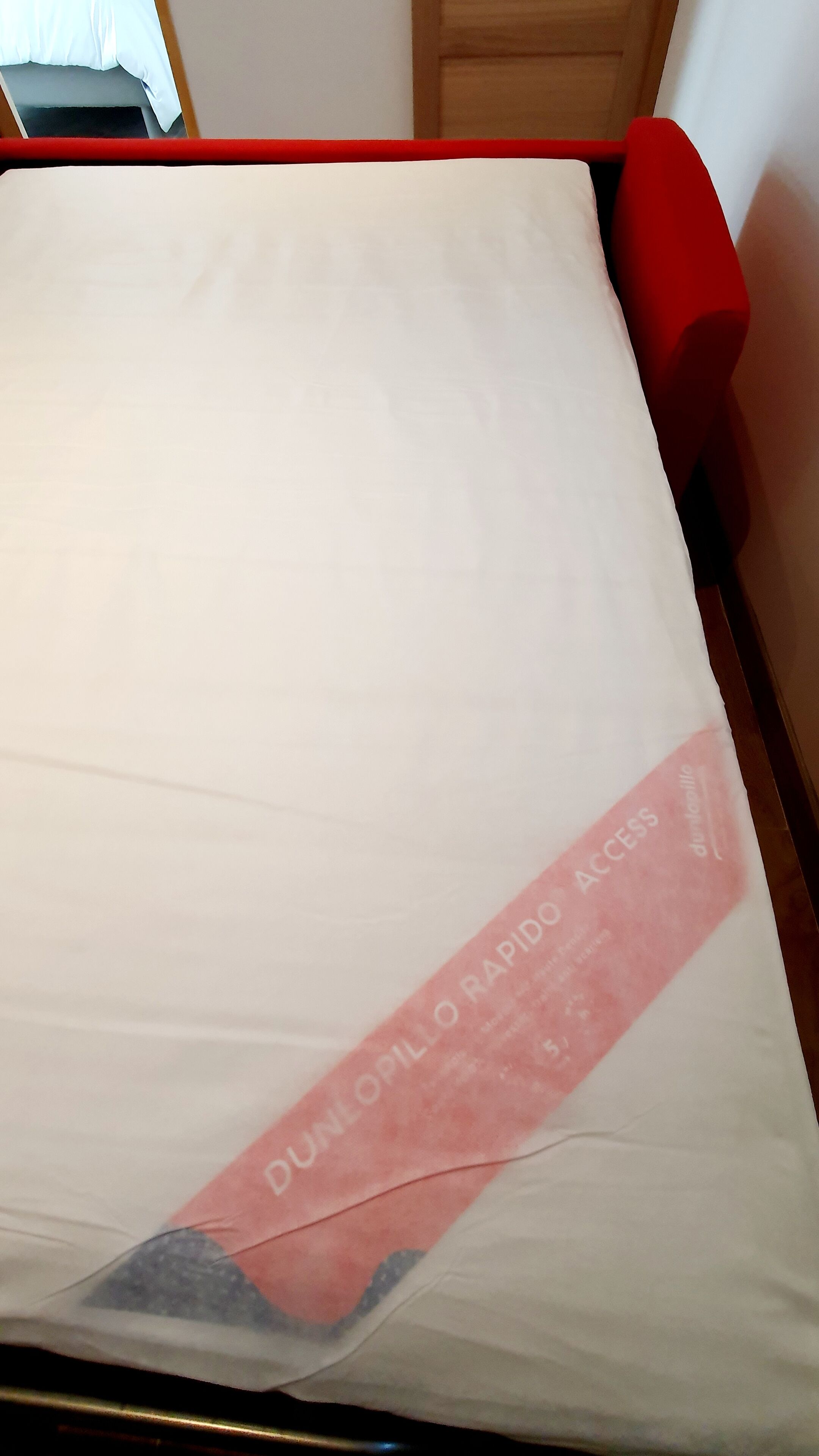 A bed with a white mattress and a red headboard.