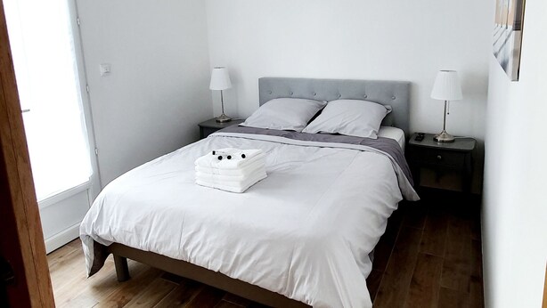 Ein Schlafzimmer mit einem Bett, zwei Nachttischen, einem Fenster und Holzboden.