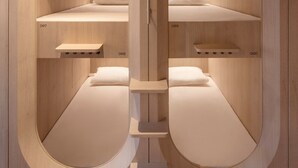 Quarto moderno e minimalista com duas camas, cada uma com cabeceira própria e uma pequena mesa de cabeceira.