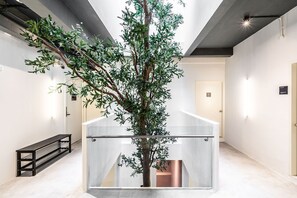 A modern interior with a central glass structure, a bench, and a door in the background. - KINN Capsule: HER Space (Female Only) (Singapore)