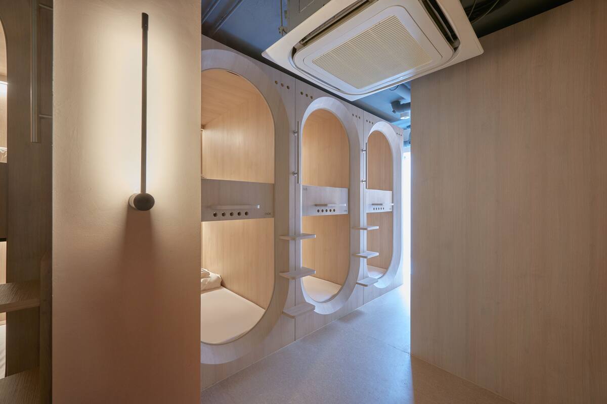 A modern restroom with three individual stalls, each with a unique curved design and a central sink.